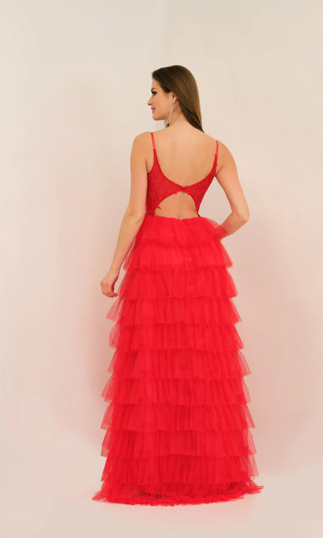 Woman wearing the Dave and Johnny Long Tiered Prom Dress 11148—a sleeveless red designer gown with a ruffled skirt, low back, and keyhole cutout—stands facing away from the camera against a plain light background.